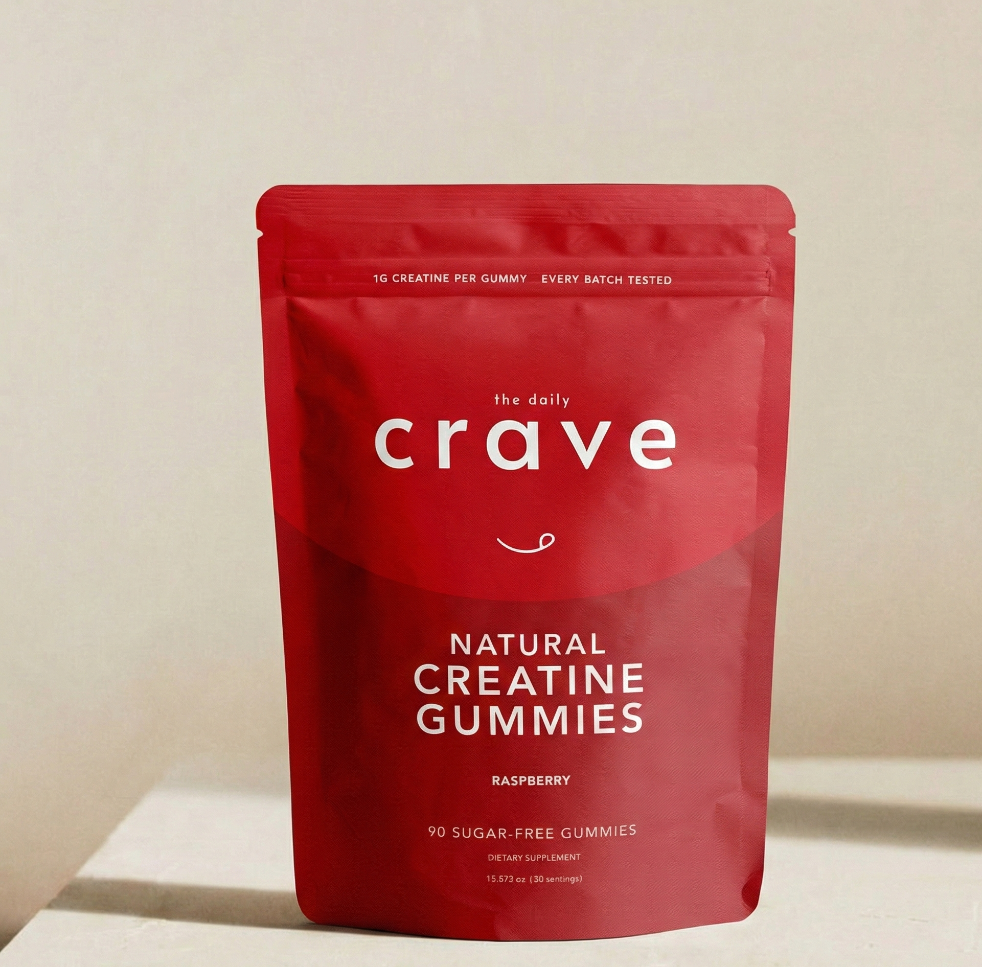 Red package of 'the daily crave' natural creatine gummies on a beige background